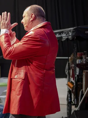Peter Schade in rotem Jackett bei einem Auftritt auf der Bühne
